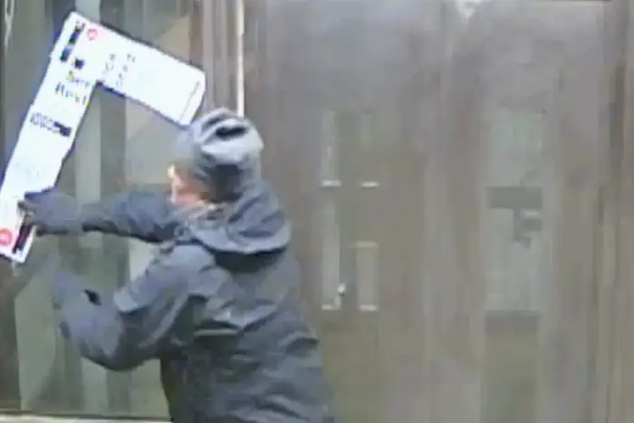 Screengrab of surveillance video showing man arranging fliers into swastika.